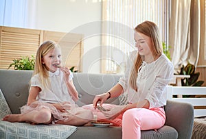 Mother and daughter having fun together at home on couch drink milk with cookies, parenting and healthy eating