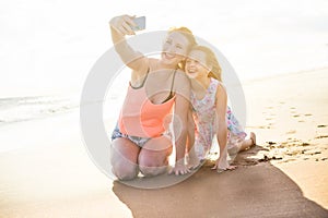 Mother and daughter having fun on tropical beach - Mum taking selfie with her kid in holiday vacation - Travel, family lifestyle