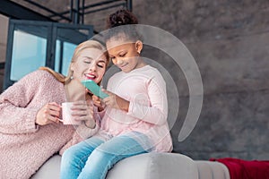 Mother and daughter having fun watching photos on phone