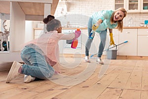 Mother and daughter having much fun while cleaning the kitchen