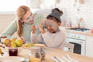 Mother and daughter having much fun cutting vegetables for salad