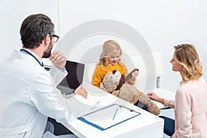 mother and daughter with her teddy bear visiting pediatrist