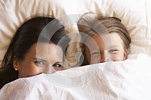 Mother And Daughter Hiding Under Bedclothes photo