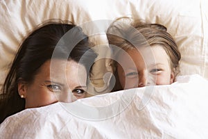 Mother And Daughter Hiding Under Bedclothes