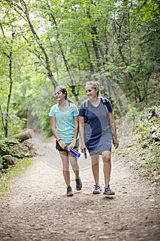 Mother and daughter hiking on a scenic mountain trail talking to each other