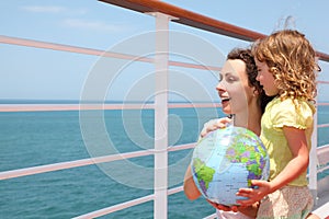 Mother and daughter holding globe on cruise liner