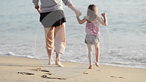 Mother and daughter holding hands and going to swim in the sea.