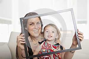 Mother and daughter holding up a picture frame and looking through it