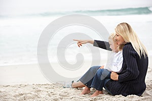 Mother And Daughter On Holiday Sitting On Beach
