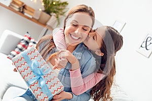 Mother and daughter at home mother`s day sitting daughter hugging mom holding present kissing