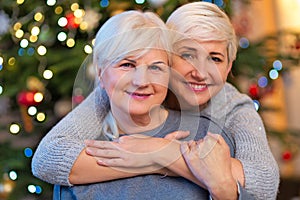 Mother and daughter hugging by Christmas tree