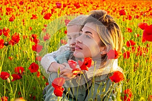 Mother with daughter hugging on the poppies meadow. Beautiful mom and daughter on a poppy field outdoor. Mother and