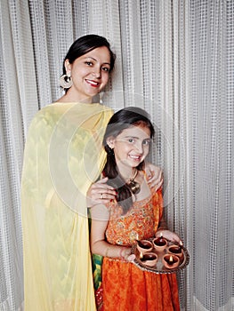 Mother and daughter with illuminated Diyas on Diwali.