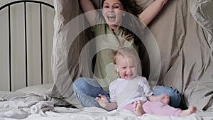Mother and daughter laughing having fun together on bed, Little baby girl and mommy playing at home