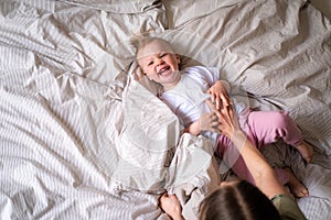 Mother and daughter laughing having fun together on bed, Little baby girl and mommy playing at home