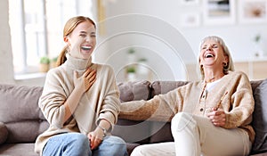 Mother and daughter laughing at joke on sofa