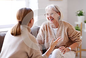 Mother and daughter laughing at joke on sofa