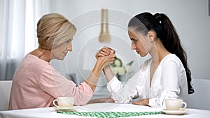 Mother and daughter-in-law looking on each other during arm wrestling battle