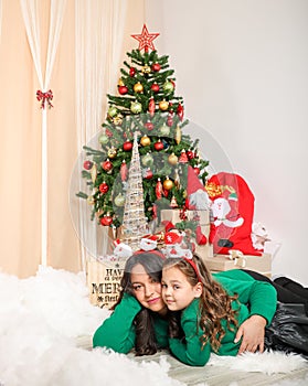 Mother and daughter laying down in front of christmas tree