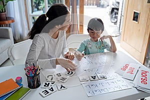 Mother and daughter learning to read and write letter at home