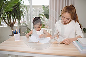 Mother and daughter learning to write, mother teaching little girl homework