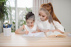 Mother and daughter learning to write, mother teaching little girl homework
