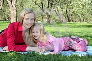 Mother with daughter lie on grass