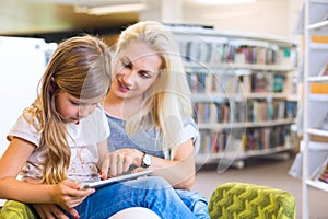 Mother with daughter look at their touchpad tablet device togeth