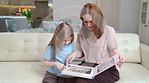 mother and daughter looking a book with photos from a family photo shoot