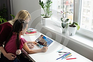 Mother and daughter looking photo book at home.