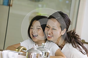 Mother And Daughter Looking At Reflection In Bathroom Mirror