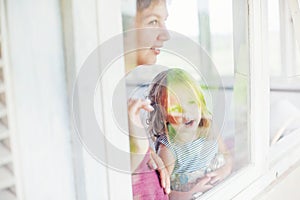 Mother and daughter looking through the window