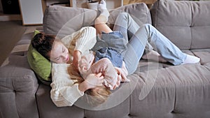 Mother and daughter lying on couch and playing, spending time together at home on daytime. Joyful, playful time