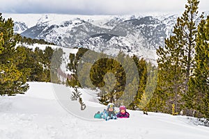 Mother and daughter lying down on a snow smiling and looking at camera. Winter ski holidays, Andorra