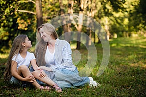 Mother and daughter lying on a grass outdoors and smiling