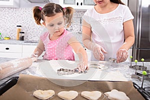 Mother And Daughter Making Cookies With Molds