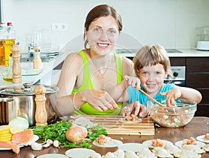 Mother with daughter making fish dumplings in the home clean ki