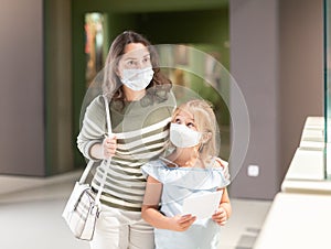 Mother and daughter in masks with guide enjoying expositions in museum