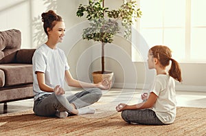 Mother and daughter meditating in living room