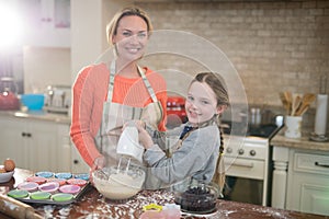 Mother and daughter mixing eggs and wheat flour in a bowl