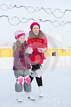 Mother and daughter mold snowballs at outdoor skating rink