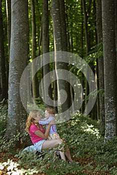 Mother and daughter moment inside the forest. Smilling and having a good time. Nature education