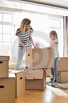 Mother and daughter packing cardboard boxes at home