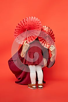 Mother and daughter with paper fans hiding