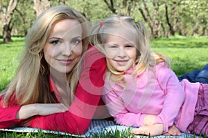 Mother and daughter in park lie on grass