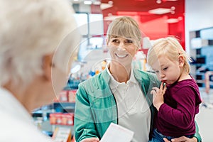 Mother with daughter in pharmacy at the counter