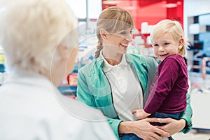 Mother with daughter in pharmacy at the counter