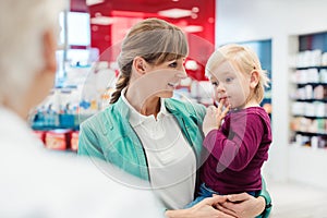 Mother with daughter in pharmacy at the counter