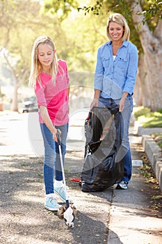 Mother And Daughter Picking Up Litter In Suburban Street