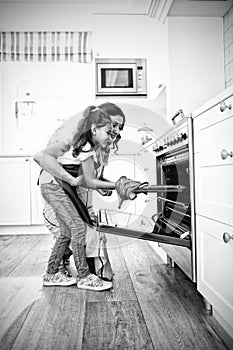 Mother and daughter placing tray of cookies in oven